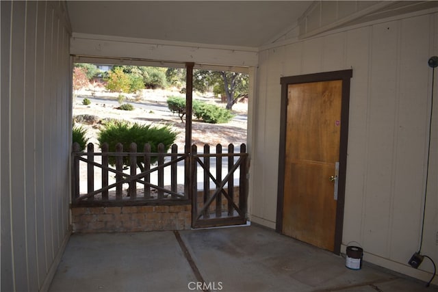 doorway featuring wood walls and vaulted ceiling