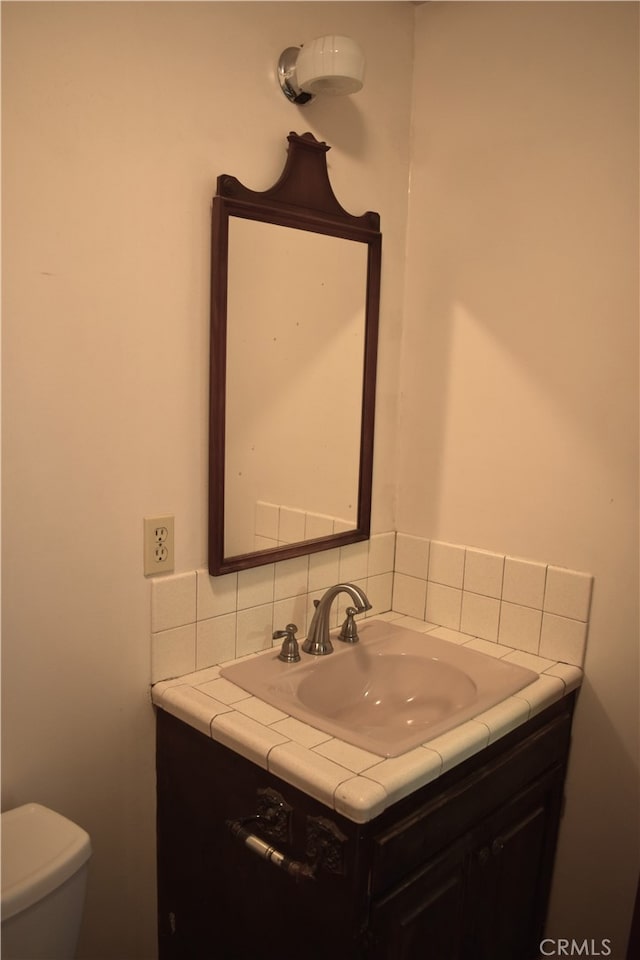 bathroom with vanity, toilet, and backsplash