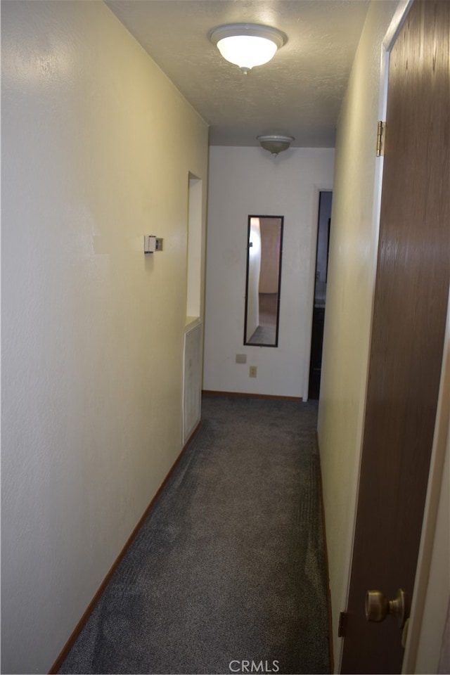 hall with dark colored carpet