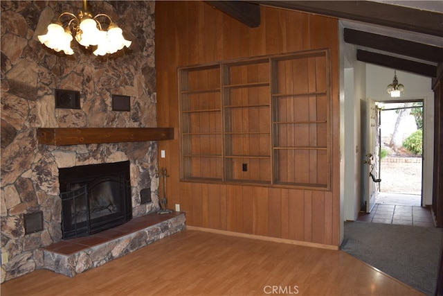 unfurnished living room featuring lofted ceiling with beams, wooden walls, wood-type flooring, and a fireplace