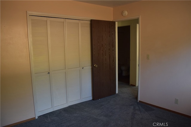 unfurnished bedroom with dark carpet and a closet