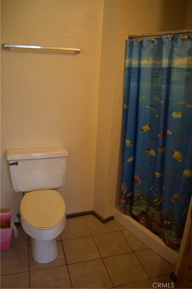 bathroom featuring toilet, a shower with curtain, and tile patterned flooring