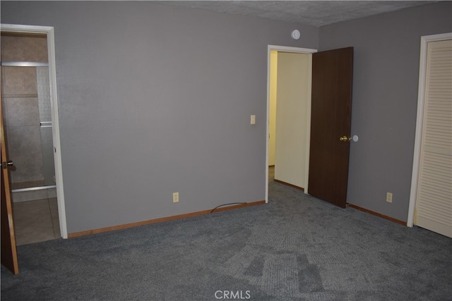 unfurnished bedroom with a textured ceiling and dark carpet