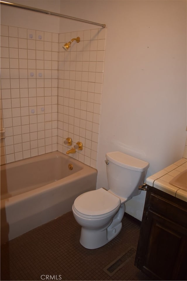 full bathroom featuring toilet, tiled shower / bath, vanity, and tile patterned flooring