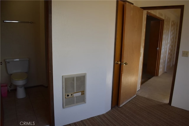 corridor featuring dark tile patterned flooring and heating unit