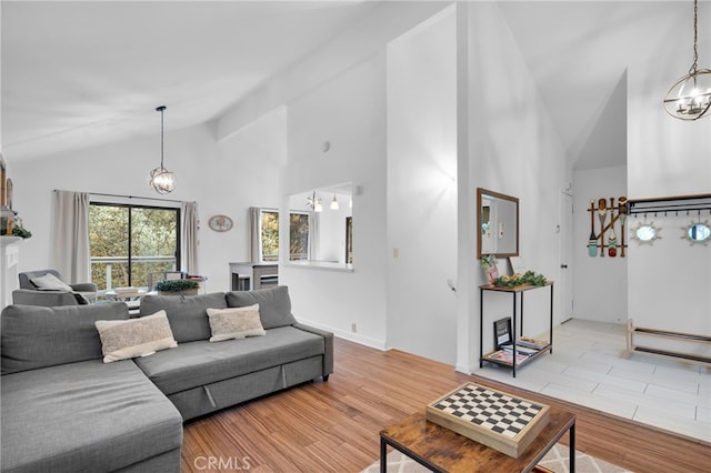 living room featuring light hardwood / wood-style floors, an inviting chandelier, beam ceiling, and high vaulted ceiling