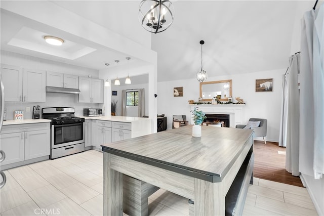 kitchen featuring gray cabinetry, light wood-type flooring, a raised ceiling, stainless steel appliances, and pendant lighting