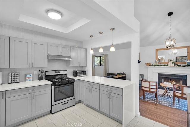 kitchen featuring gray cabinets, stainless steel range with gas cooktop, decorative light fixtures, and light hardwood / wood-style floors