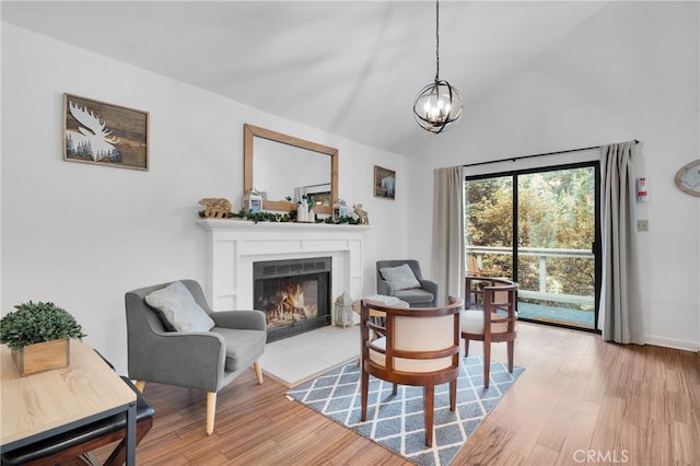 living room with an inviting chandelier, light hardwood / wood-style flooring, and high vaulted ceiling