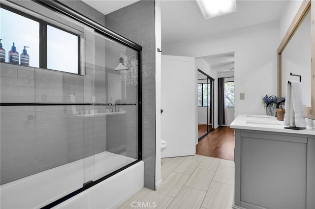 full bathroom featuring toilet, combined bath / shower with glass door, hardwood / wood-style flooring, and vanity