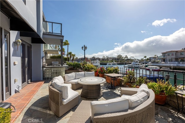 view of patio / terrace featuring a water view, an outdoor living space with a fire pit, a balcony, and area for grilling