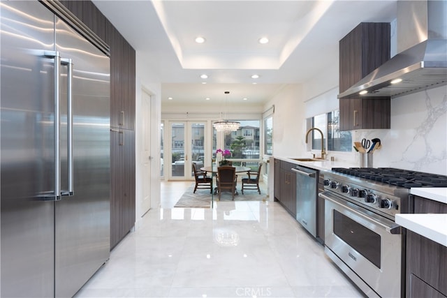 kitchen with pendant lighting, wall chimney exhaust hood, a wealth of natural light, and high end appliances