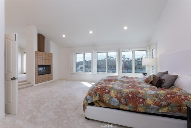 carpeted bedroom with a fireplace and high vaulted ceiling