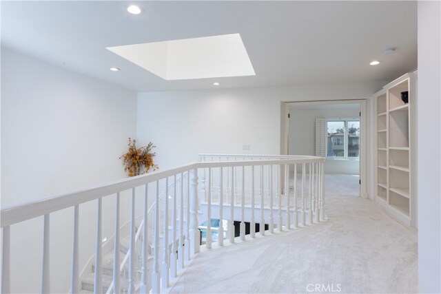 corridor featuring light colored carpet and a skylight