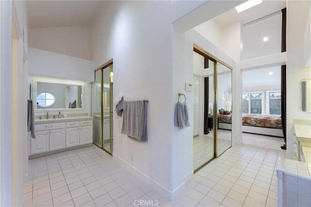 bathroom featuring vanity, high vaulted ceiling, tile patterned floors, and a wealth of natural light