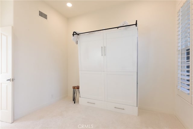 unfurnished bedroom featuring light carpet and a closet