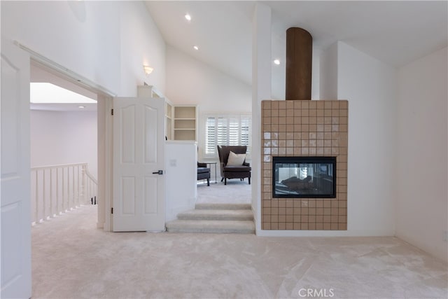 unfurnished living room with light carpet, high vaulted ceiling, and a tile fireplace