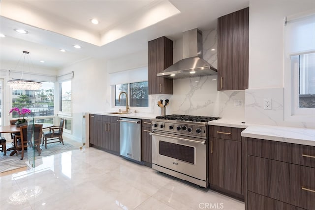 kitchen with appliances with stainless steel finishes, sink, backsplash, hanging light fixtures, and wall chimney exhaust hood