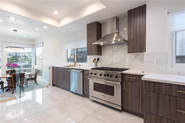 6218 Tobruk Ct, Long Beach, CA 90803 - kitchen with wall chimney range hood, appliances with stainless steel finishes, a sink, dark brown cabinetry, and decorative backsplash