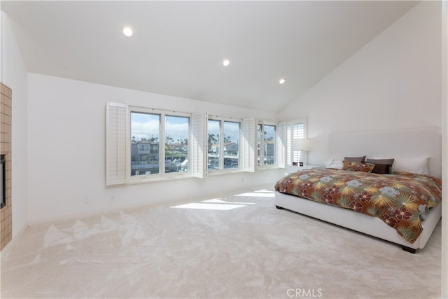 carpeted bedroom featuring high vaulted ceiling and a fireplace