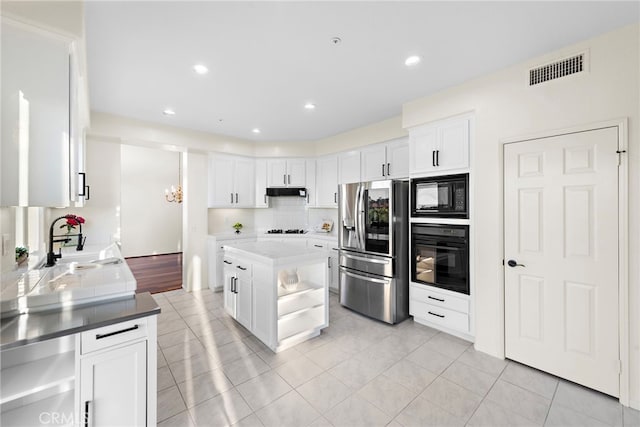 kitchen featuring black appliances, white cabinets, sink, light tile patterned floors, and a kitchen island