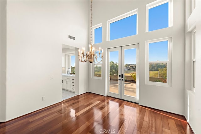 spare room featuring french doors, light hardwood / wood-style flooring, and a high ceiling