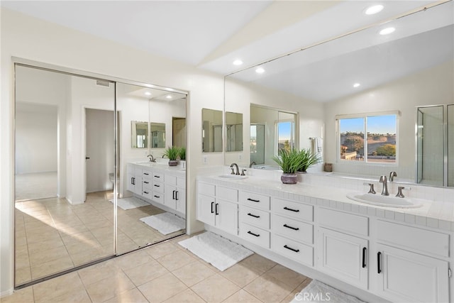 bathroom with tile patterned flooring, vanity, vaulted ceiling, and a shower with shower door