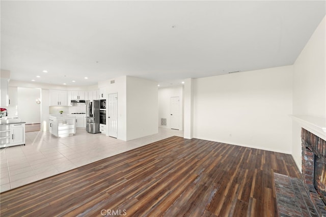 unfurnished living room featuring light hardwood / wood-style floors and a brick fireplace