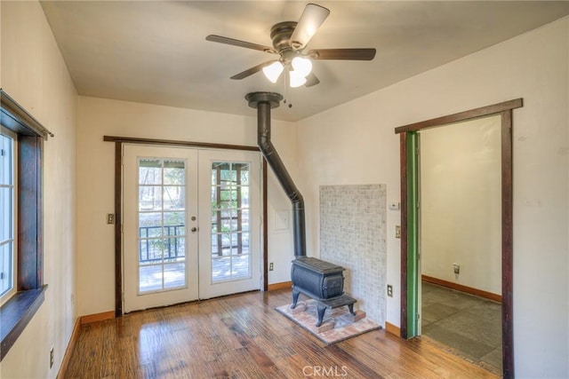 doorway with french doors, ceiling fan, hardwood / wood-style floors, and a wood stove