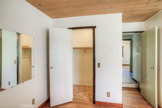 unfurnished bedroom featuring a walk in closet, wooden ceiling, and light hardwood / wood-style flooring