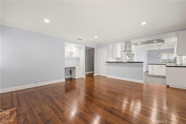 unfurnished living room featuring wood-type flooring, crown molding, and sink