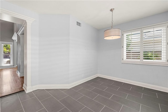 empty room featuring dark tile patterned floors and a wealth of natural light