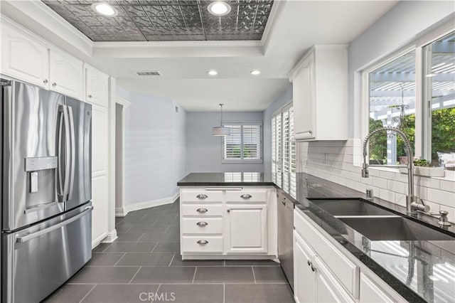 kitchen featuring appliances with stainless steel finishes, decorative light fixtures, white cabinetry, and sink