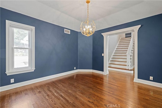 spare room featuring hardwood / wood-style flooring and an inviting chandelier