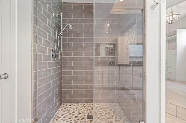 bathroom with a shower with shower door and a notable chandelier