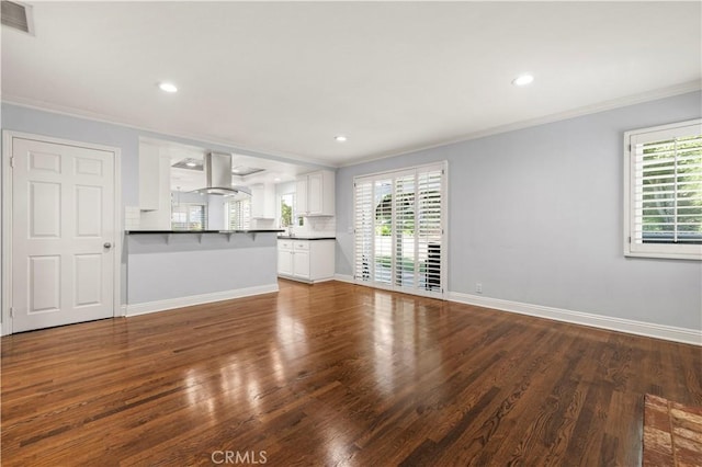 unfurnished living room with a healthy amount of sunlight, dark hardwood / wood-style flooring, and ornamental molding