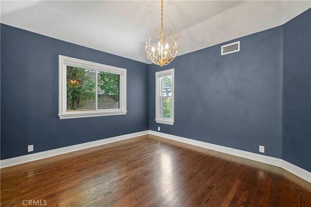 unfurnished room featuring wood-type flooring and a chandelier