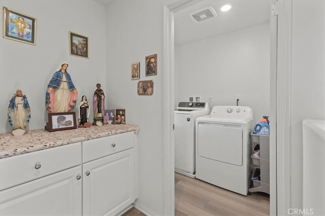 laundry area with independent washer and dryer and light hardwood / wood-style floors