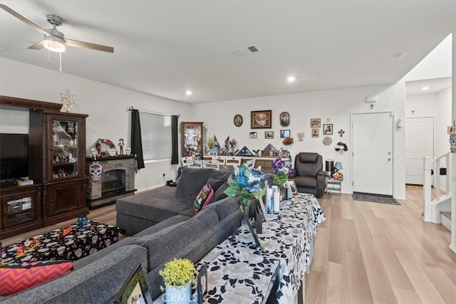 living room featuring light hardwood / wood-style flooring, a fireplace, and ceiling fan