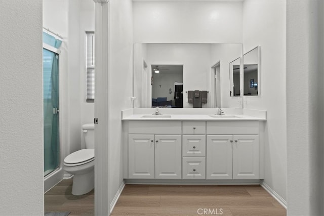 bathroom featuring vanity, toilet, a shower with shower door, and hardwood / wood-style floors