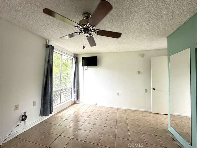 tiled spare room with ceiling fan and a textured ceiling