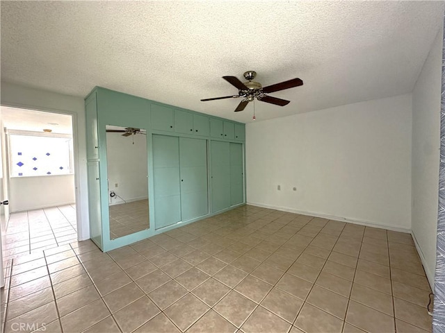 unfurnished bedroom featuring ceiling fan, light tile patterned floors, a textured ceiling, and a closet