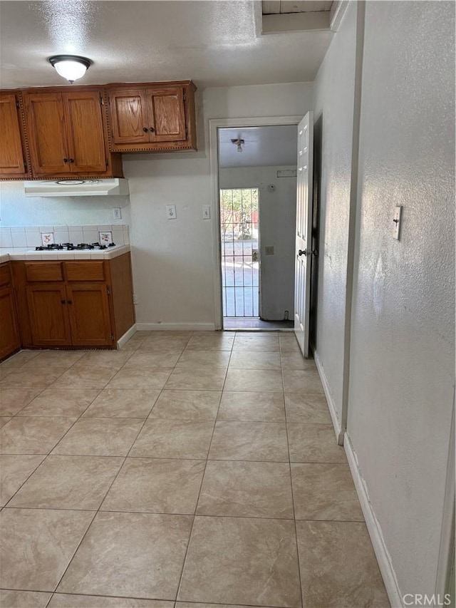 kitchen featuring a textured ceiling, light tile patterned flooring, and white gas cooktop