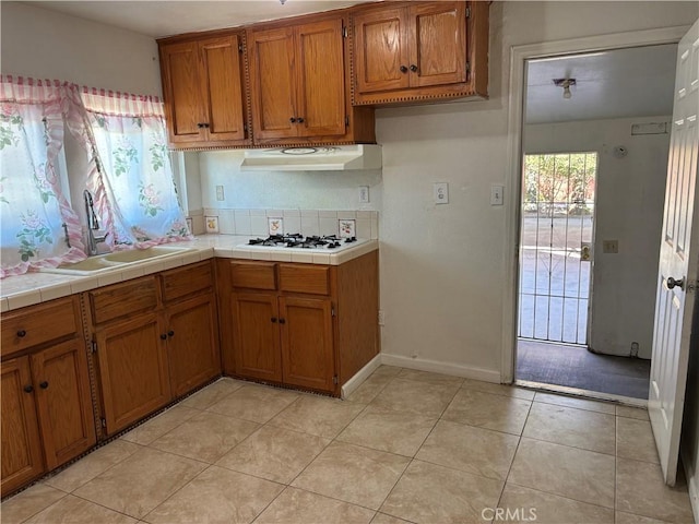 kitchen featuring sink, white gas stovetop, tile countertops, and light tile patterned flooring