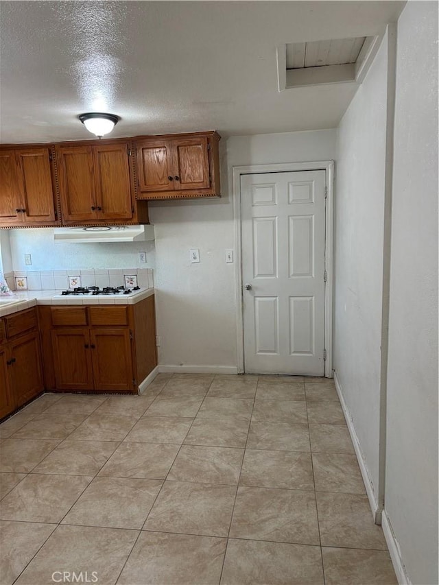 kitchen featuring a textured ceiling, light tile patterned floors, and white gas stovetop