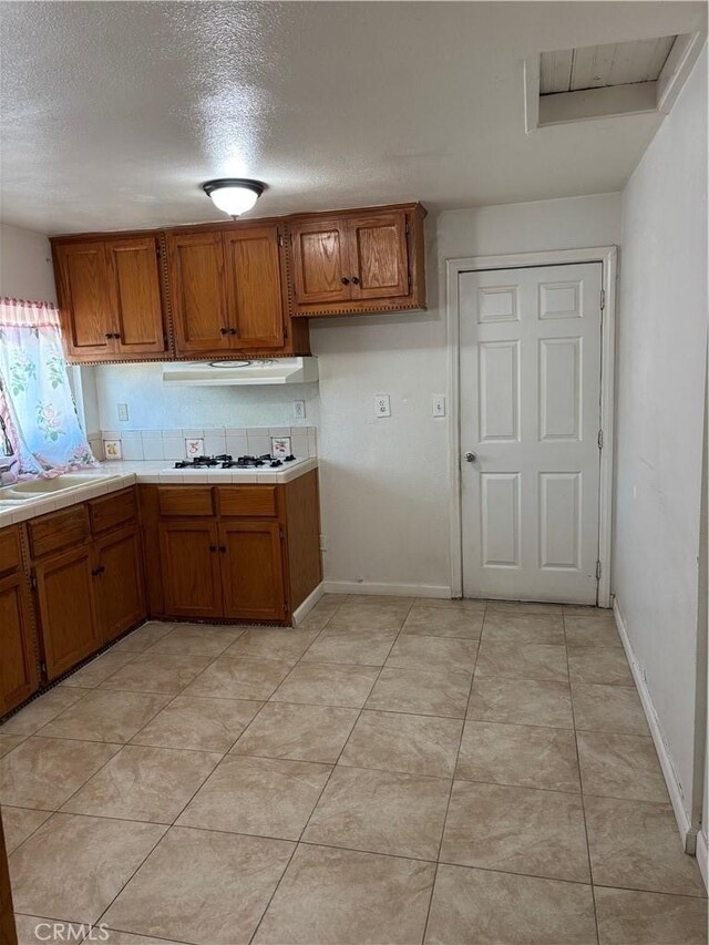 kitchen featuring light tile patterned floors, white gas cooktop, sink, and a textured ceiling