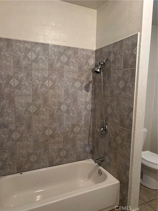 bathroom with toilet, tiled shower / bath combo, and tile patterned floors