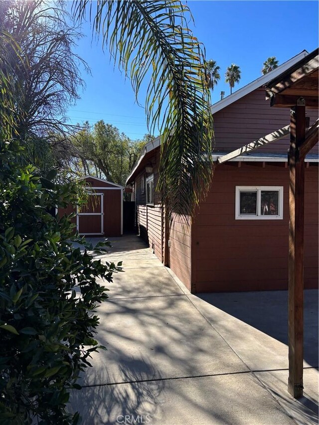 view of side of home with a patio area and a storage shed