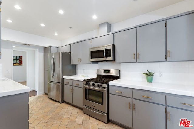 kitchen featuring appliances with stainless steel finishes, tasteful backsplash, and gray cabinets