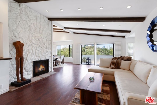 living room featuring dark wood-type flooring, vaulted ceiling with beams, a fireplace, and plenty of natural light